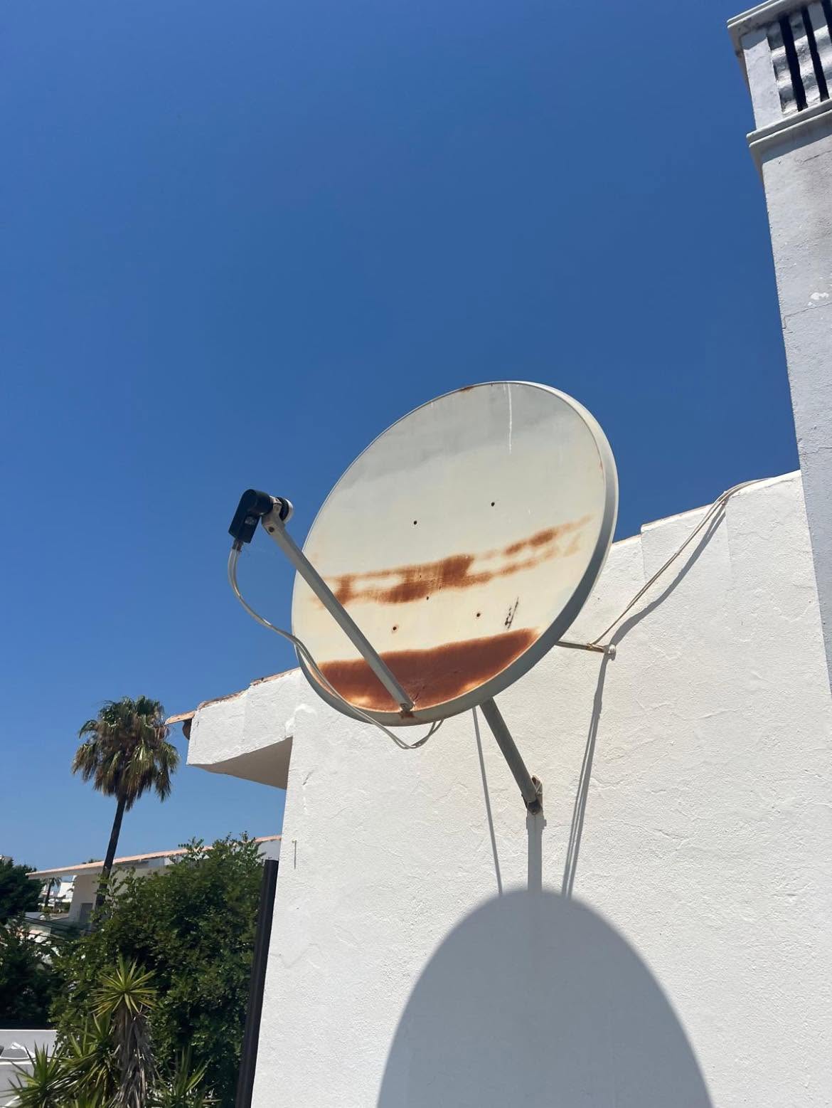 Before: a rusty, disused satellite dish bolted to a white villa wall with cables hanging loose
